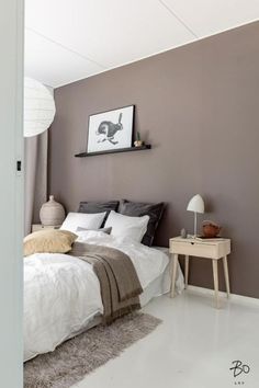 a bed sitting in a bedroom next to a white table and lamp on top of a hard wood floor