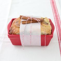 a red container filled with bread and cinnamon sticks on top of a white table cloth