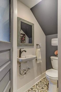 a bathroom with a toilet, sink and mirror on the wall next to an open door