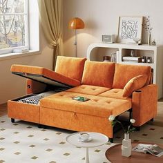 a living room with an orange couch and coffee table in the corner, next to a window