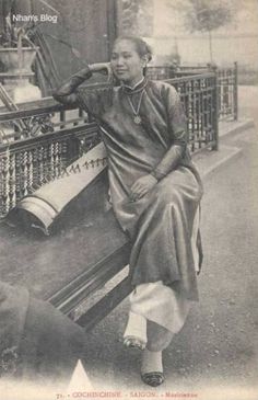 an old black and white photo of a woman sitting on a bench looking at something