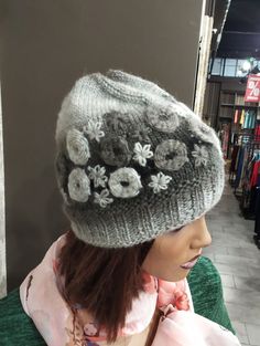 a mannequin wearing a gray hat with flowers on it's brim