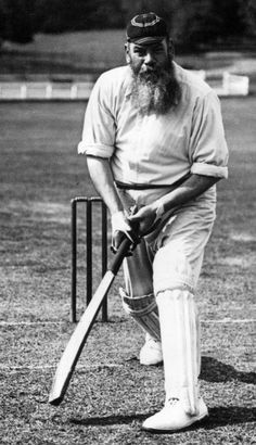 an old photo of a man with a beard holding a baseball bat and standing next to a ball