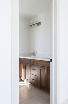 an empty bathroom with wooden cabinets and white walls