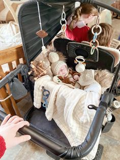 a baby in a stroller with other toys and accessories hanging from it's back