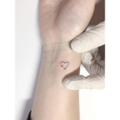 a person with a small heart tattoo on their left wrist and the other hand behind her