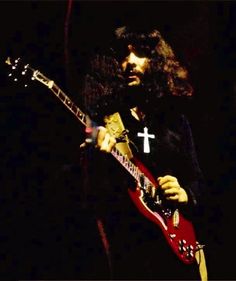 a man with long hair playing an electric guitar