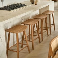 three wooden stools sitting on top of a counter next to a stove and oven