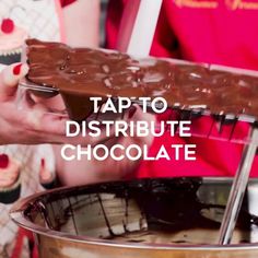 a person holding a piece of chocolate in front of a large metal bowl with the words tap to distribute chocolate on it