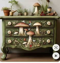 a green dresser with mushrooms painted on the drawers and plants growing out of it's sides