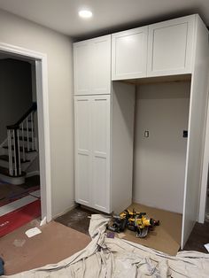 an empty room with white cabinets and tools on the floor in front of it is being worked on