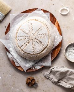 a round cake sitting on top of a wooden plate covered in icing next to other items