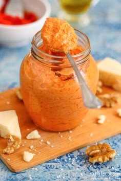 a jar filled with food sitting on top of a wooden cutting board next to nuts