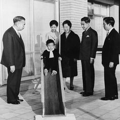 a group of people standing next to each other in front of a building on a sidewalk