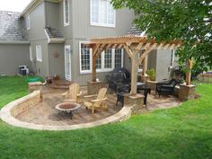 a patio with chairs and an outdoor fire pit in the middle of it next to a house