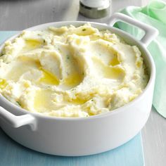 a white bowl filled with mashed potatoes sitting on top of a blue table cloth