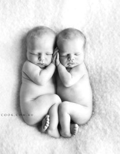 two babies are laying on top of each other in the middle of a white blanket