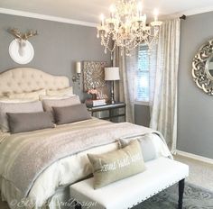 a large bed sitting in a bedroom next to a window with a chandelier