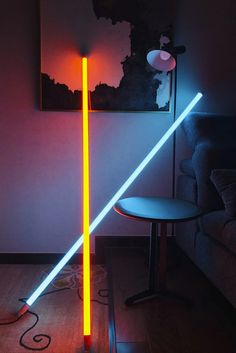 two neon lights in the corner of a room next to a chair and table with a lamp on it