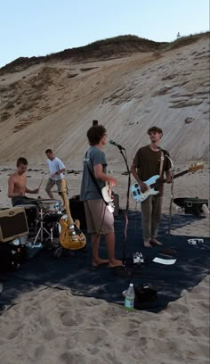 some people are playing music on the beach and one person is singing into a microphone