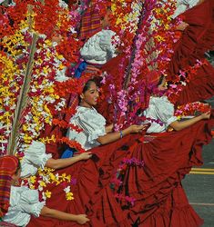 people dressed in red and white are dancing with streamers on their heads as they float down the street