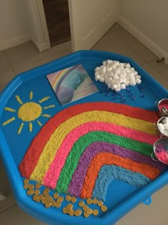 a child's play table with rainbow rugs and toys on the floor next to it