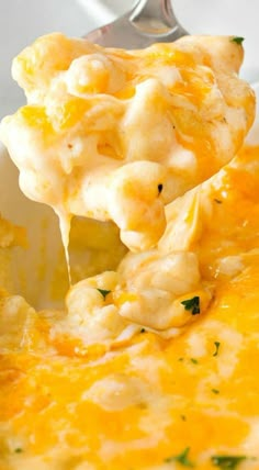 a spoon full of macaroni and cheese being lifted from a casserole dish