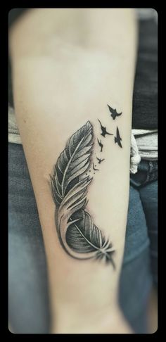 a black and white photo of a feather with birds flying around it on the arm