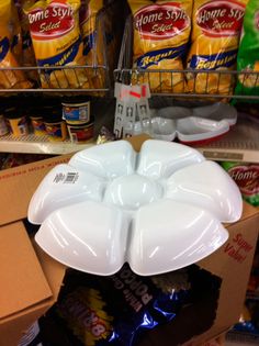 a large white flower shaped bowl sitting on top of a shelf in a grocery store