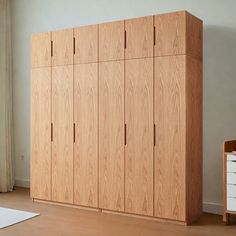 a large wooden cabinet sitting next to a window in a room with wood floors and white walls