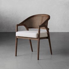 a wooden chair with a white cushion on the back and armrests, in front of a gray wall