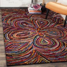 a colorful rug on the floor with a chair in front of it and a plant