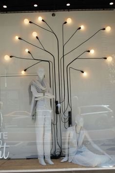 mannequins sit in front of a window with lights