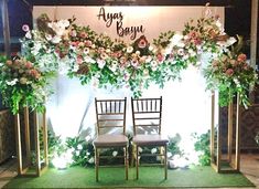 two chairs sitting on top of a green carpeted floor next to flowers and greenery