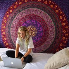 a woman sitting on top of a bed with a laptop computer in front of her