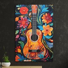 an acoustic guitar painted with flowers and leaves on a black wall next to a potted plant