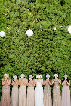 a group of women standing next to each other in front of a lush green wall