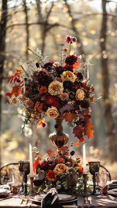 a centerpiece with flowers and candles is on top of a table in the woods