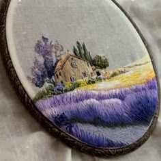 a hand embroidered picture of a lavender field with a house in the distance on it