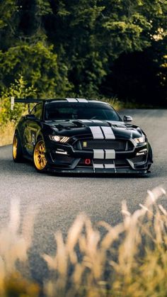 a black sports car with yellow rims driving down the road