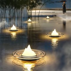 there are many lights that are floating in the water and reflecting on the wet ground