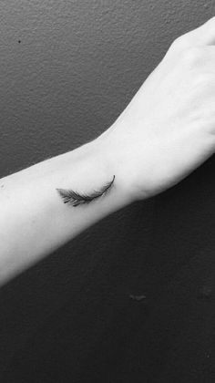 a black and white photo of a person's arm with a feather tattoo on it