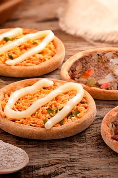 three pizzas with toppings sitting on top of a wooden table