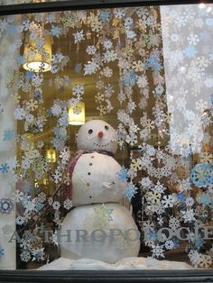 a snowman is in the window of a storefront with blue and white snowflakes