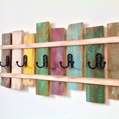 a wooden shelf with hooks on it and several different colored wood planks attached to the wall