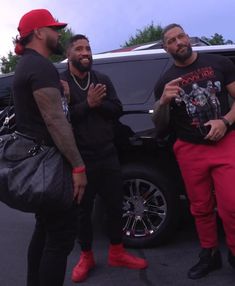 three men standing next to each other in front of a car