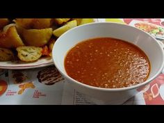 a bowl of soup next to a plate of bread on a table with other food