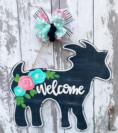 a black cow with flowers on it and a welcome sign attached to the front door