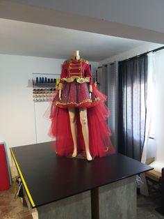 a mannequin wearing a red dress on top of a black counter in a room