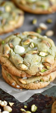 a stack of cookies with white chocolate and pistachios on top sitting on wax paper